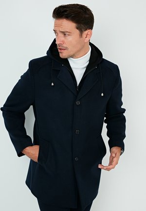 Manteau bleu marine avec capuche, fabriqué en matériau doux. Comprend deux poches avant et un design à boutons. La couche intérieure présente un sweat à capuche noir contrastant.
