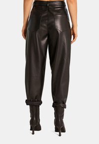 Zwarte leren baggy broeken met opgerolde boorden, uitgerust met twee achterzakken en een gladde textuur, gestyled met hoge laarzen.