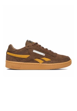 Brauner Wildleder-Reebok-Sneaker mit senfgelben Akzenten, Schnürverschluss und Gummisohle auf weißem Hintergrund.