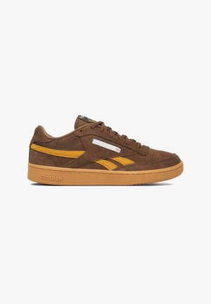 Brauner Wildleder-Reebok-Sneaker mit senfgelben Akzenten, Schnürverschluss und Gummisohle auf weißem Hintergrund.