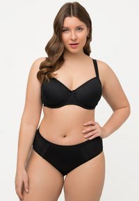 Soutien-gorge rembourré noir avec bretelles réglables et dentelle, associé à une culotte noire taille haute présentant des panneaux latéraux texturés.