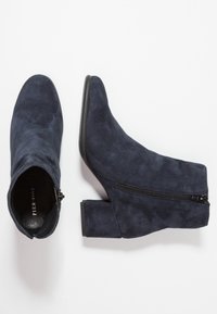 Marineblaue Wildleder-Stiefeletten mit einem blockartigen Absatz und seitlichem Reißverschluss. Das Design verfügt über eine spitze Zehenform und eine glatte Oberfläche.