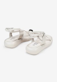 Sandali platform bianchi con sottili cinghie e suola arrotondata. I sandali presentano un design minimalista e una texture liscia, con una fibbia regolabile.