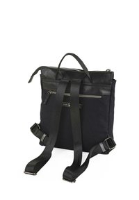Mochila de lona negra con parte superior de cuero, doble asa, correas ajustables y un bolsillo frontal con cremallera. Presenta un diseño elegante y minimalista.