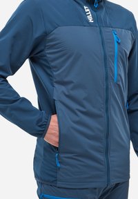 Veste en polaire de couleur bleu foncé avec des accents bleu clair, dotée d'une fermeture éclair intégrale, de poches latérales et d'un panneau supérieur texturé. Légère et respirante.