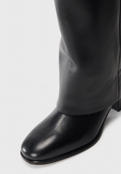 Black leather ankle boot with a rounded toe, smooth texture, moderate heel, and slight slouch at the upper shaft.