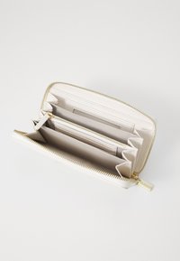 Portafoglio in pelle bianca con zip dorata, multiple fessure per carte e scomparti interni per banconote e monete, con una finitura strutturata.