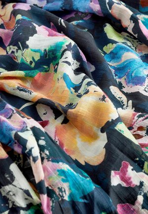 Tissu sombre avec un motif floral abstrait vibrant en bleu, vert, jaune, rose et blanc, montrant de douces plis et une texture.