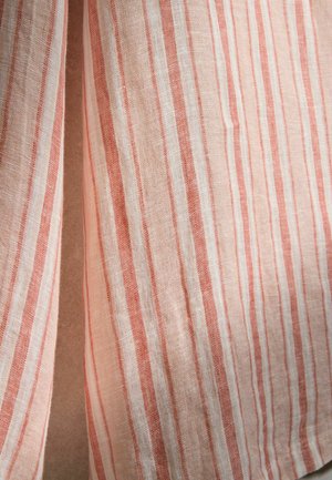 Lengvas audinys su vertikaliomis oranžinėmis ir baltomis juostelėmis, šiek tiek sulankstyta, kad būtų parodyta tekstūra ir pynimo detalės.