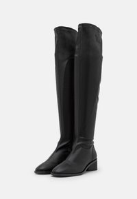 Botas negras de cuero suave hasta la rodilla, con un tacón cuadrado, puntera afilada y cremallera en el lado interior. Diseño simple sin adornos.