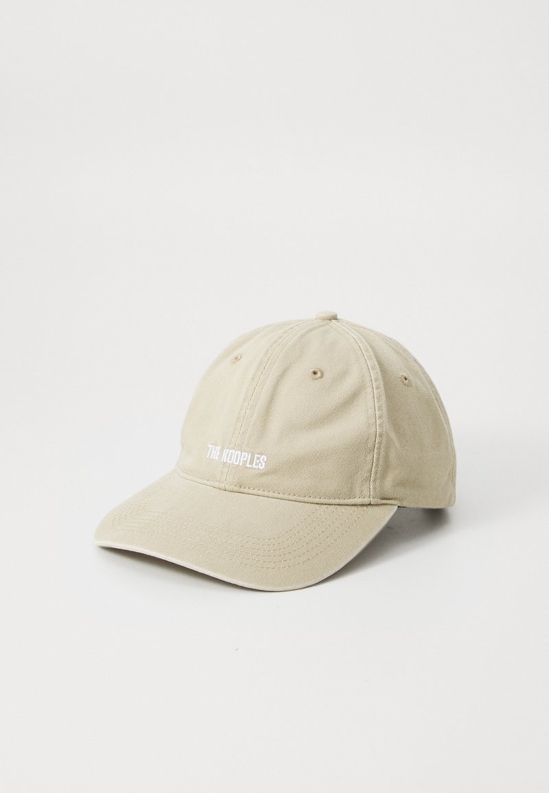 Beige katoenen pet met een gebogen klep, voorzien van witte geborduurde tekst "THE KOOPLES" aan de voorkant en zes ventilatie-oogjes op de kroon.