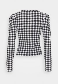 Mustavalkoinen houndstooth-takki, istuva malli, pitkät hihat, rakenteelliset olkapäät, teksturoitu kangas, takanäkymä, jossa ei ole näkyviä suljintoja.