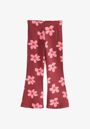 Piros szárában bővülő nadrág, nagy rózsaszín és piros virágmintával, amely egyenletesen oszlik el a szöveten, fehér háttér előtt bemutatva.