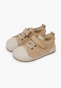 Scarpe in pelle beige con punta in gomma e fasce in Velcro. Forma arrotondata con una superficie testurizzata e suola bianca a contrasto.