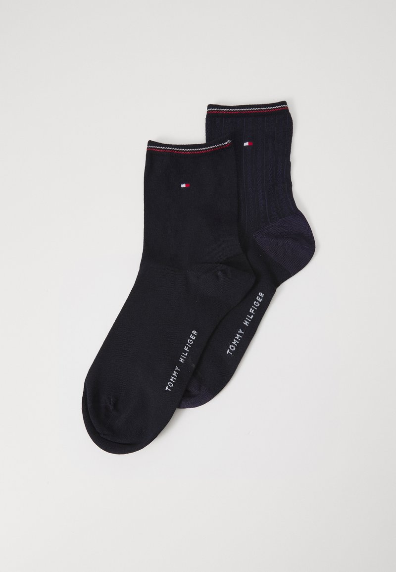 Un par de calcetines en azul marino oscuro y textura estampada. Uno presenta un diseño acanalado; ambos tienen un pequeño logo y un cuello en contraste.