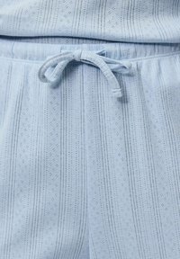 Svjetloplava tkanina s vertikalnim očnim prugama i vezanom vrpcom na struku od odjeće.