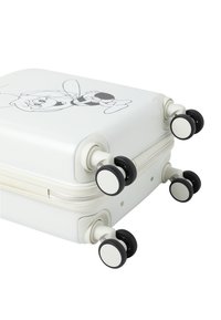 Valise rigide blanche avec un design de personnage de cartoon, quatre roues noires, surface lisse et fermeture éclair.