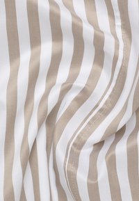 Randigt tyg i vitt och ljusbeige, med en slät textur och diagonala linjer samt en subtil lyster, som visar upp noggrant sydda kanter.