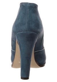 Sininen mokkanahkainen korkokenkä, jossa on kapeneva muotoilu, kärjessä terävä suunta ja sileä pinta. Kengässä on myös leikattu yksityiskohta sivuilla.