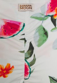 Tecido de fato de banho floral com padrões de melancia rosa e flores laranja sobre um fundo branco, com textura franzida e etiqueta Banana Moon.