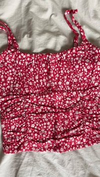Top corto floreale rosso con spalline sottili, con un design arricciato e piccoli fiori bianchi su un tessuto testurizzato.