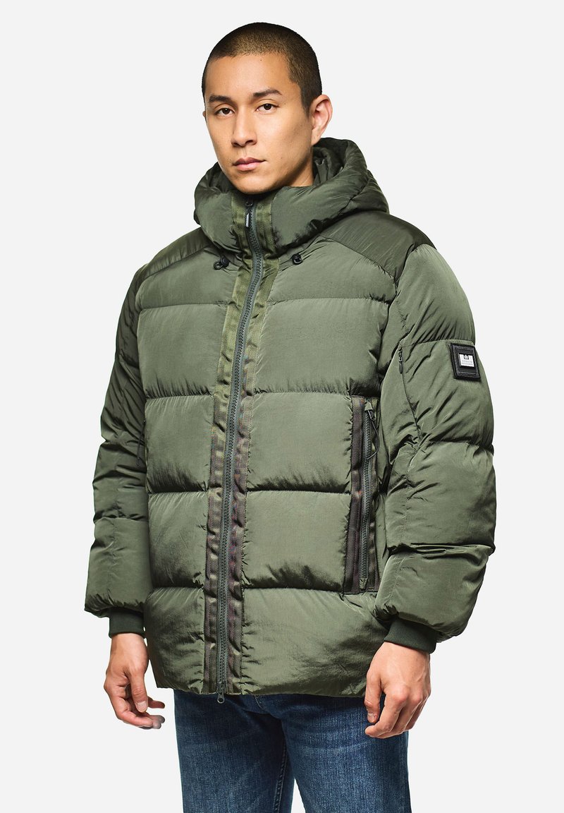 Grüne Puffjacke mit durchgehendem Reißverschluss, Kapuze und zwei seitlichen Taschen. Besitzt steppartige Abschnitte und ein Logo-Patch am linken Ärmel.