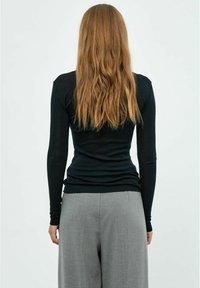 Schwarzes Langarmoberteil aus dehnbarem Material mit tailliertem Design. Die Rückansicht zeigt eine glatte Textur und subtile Nähdetails.
