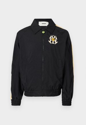 Giacca nera con zip e colletto, caratterizzata da strisce laterali gialle e un logo grafico sul petto. Realizzata in tessuto leggero con polsini elastici.