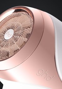 Gros plan sur un rasoir à tissu en rose gold et blanc avec un couvercle de lame perforé et un logo décoratif sur le manche.