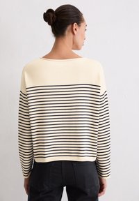 Roomwit en marineblauw gestreepte trui met een losse pasvorm, brede halslijn en lange mouwen. Zachte textuur; geribbelde zoom bij de taille en manchetten.