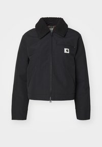 Zwarte cropped jas met een rits aan de voorkant, voorzien van een sherpa kraag, zijzakken en een klein merklabel op de borst. Gladde textuur.