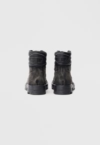 Botines negros hasta el tobillo con tejido texturizado y detalles en cuero liso. Cuentan con una suela ligeramente resistente y un cuello acolchado. Branding sutil en los talones.