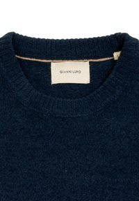 Granatowy sweter z dzianiny z okrągłym dekoltem, fakturowaną powierzchnią i naszywką z napisem "GIANNI LUPO" wszytą wewnątrz kołnierza.