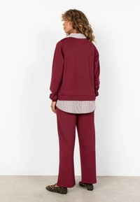 Bordo bluza i pasujące spodnie uszyte z miękkiego materiału, z warstwowym wyglądem, pod spodem koszula zapinana na guziki w paski.