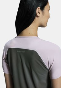 Short-sleeve athletic shirt featuring a light pink front and dark green back panel with a textured finish and reflective detail.