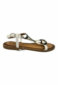 Sandalias planas blancas con suela marrón, con una correa verde texturizada y cuentas decorativas en la parte superior. Detalle de hebilla ajustable en el tobillo.