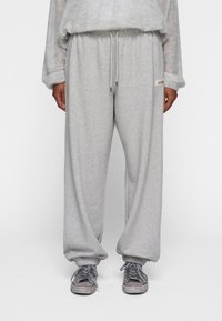 Grå fleece sweatpants med en afslappet pasform, elastisk talje med snor og ribbede manchetter. Har et lille logo-patch på siden.