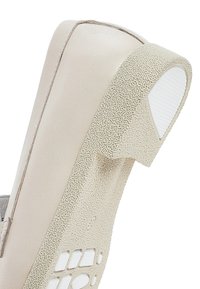 Scarpa beige con un tallone posteriore texturizzato e maculato e una parte anteriore liscia. Presenta una suola in gomma bianca con fori per la ventilazione.
