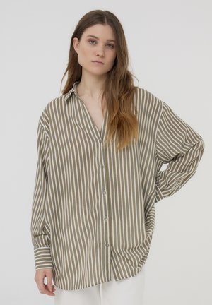 Camicia a maniche lunghe a righe marrone chiaro e bianco, con un fit rilassato e colletto. Il tessuto sembra morbido con una superficie liscia.