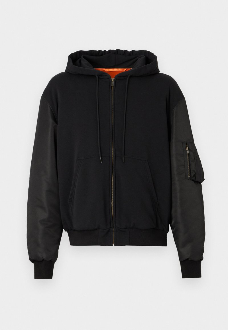 Sort lynlås-hættetrøje med en glat stofkrop og satinlignende ærmer. Har en forlomme og en ekstra lynlåslomme på armen.