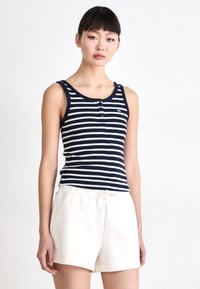 Navy and white striped tank top with a rounded neckline, three-button placket, and paired with light-colored shorts. Smooth cotton texture.