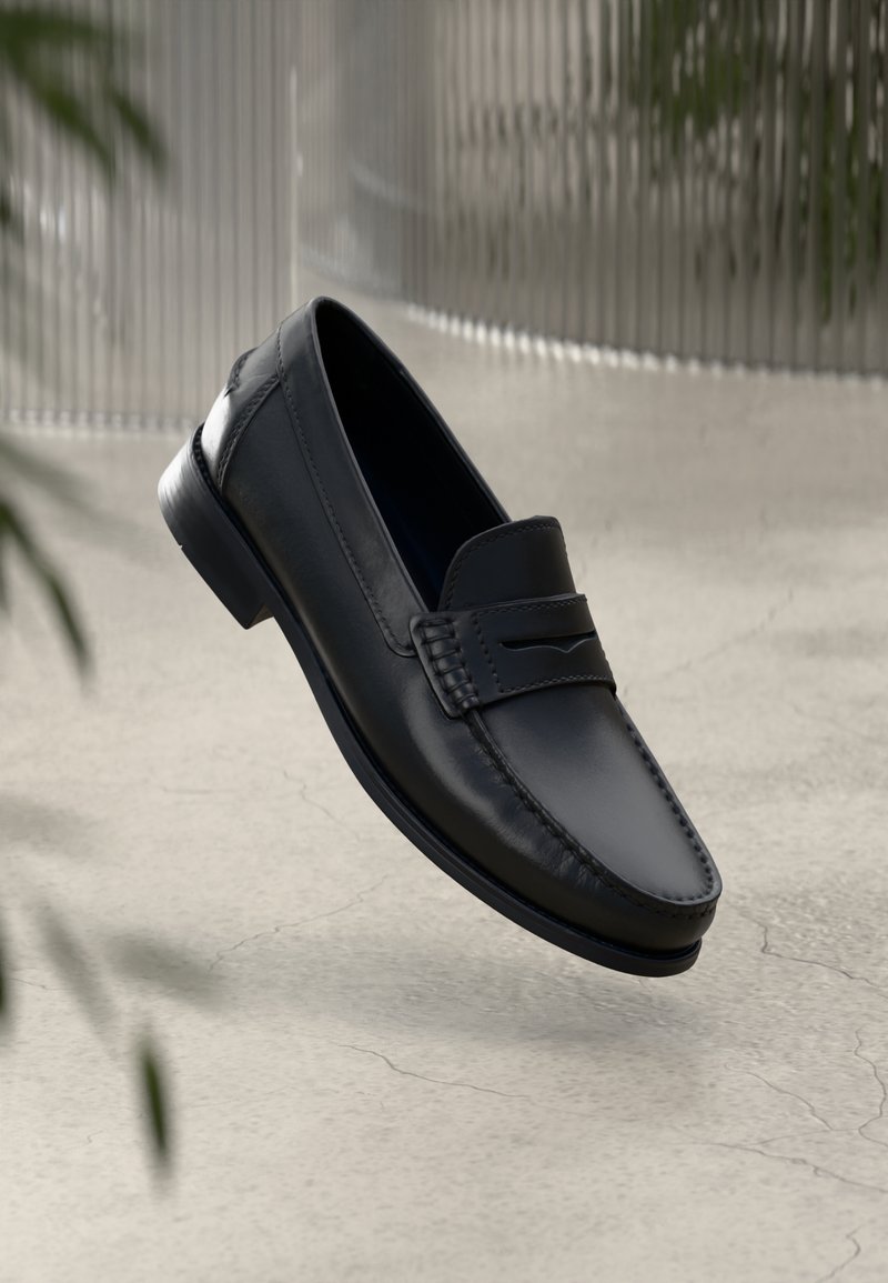 Mocassin en cuir noir avec des coutures apparentes et une fente décorative sur l’empeigne, présenté sur un fond neutre et texturé.