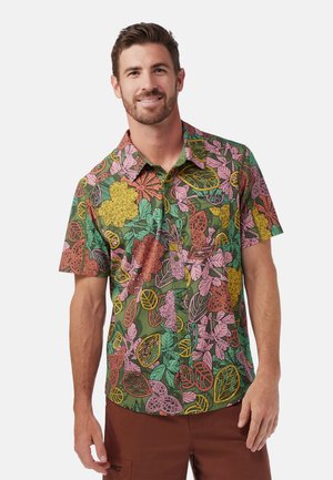 Camisa de botones de manga corta con un vibrante patrón floral en rosa, amarillo y verde sobre un fondo verde oscuro; tejido ligero.