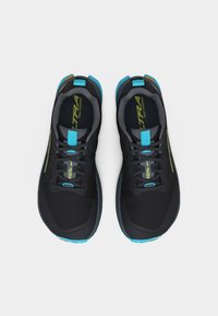 Ζευγάρι μαύρα παπούτσια για τρέξιμο σε μονοπάτια με μπλε λεπτομέρειες και πατούσες με μοτίβο, φωτογραφημένα από ψηλά σε λευκό φόντο.