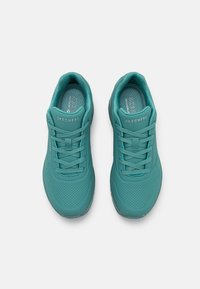 Teal Skechers sneakers with a smooth synthetic upper, rounded toe, perforated detailing, flat laces, and textured insole.