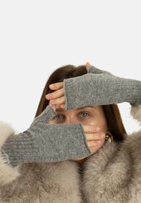 Szare rękawiczki bezpalcowe wykonane z teksturowanej wełny, z prążkowanym wzorem dzianiny i miękkim wykończeniem, częściowo zasłonięte przez dłonie.