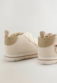 Beige corduroy kingad, millel on beežist nahast aktsendid, madal lõige, tekstuurpind ja valge kummist tallaga, millel on kerged beežid triibud.