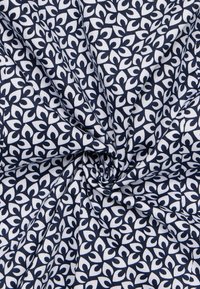 Tessuto di cotone con un design blu navy e bianco, caratterizzato da un motivo floreale ripetuto e una texture liscia.