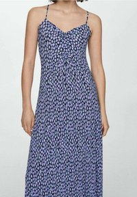 Robe maxi fleurie avec bretelles spaghetti, dotée d'un corsage ajusté et d'une jupe ample aux couleurs violet et noir avec des accents verts.