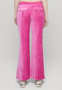 Rózsaszín, bő szárú nadrág puha bársony anyagból, sima tapintású. Két hátsó zsebbel és rugalmas derékpánttal rendelkezik.